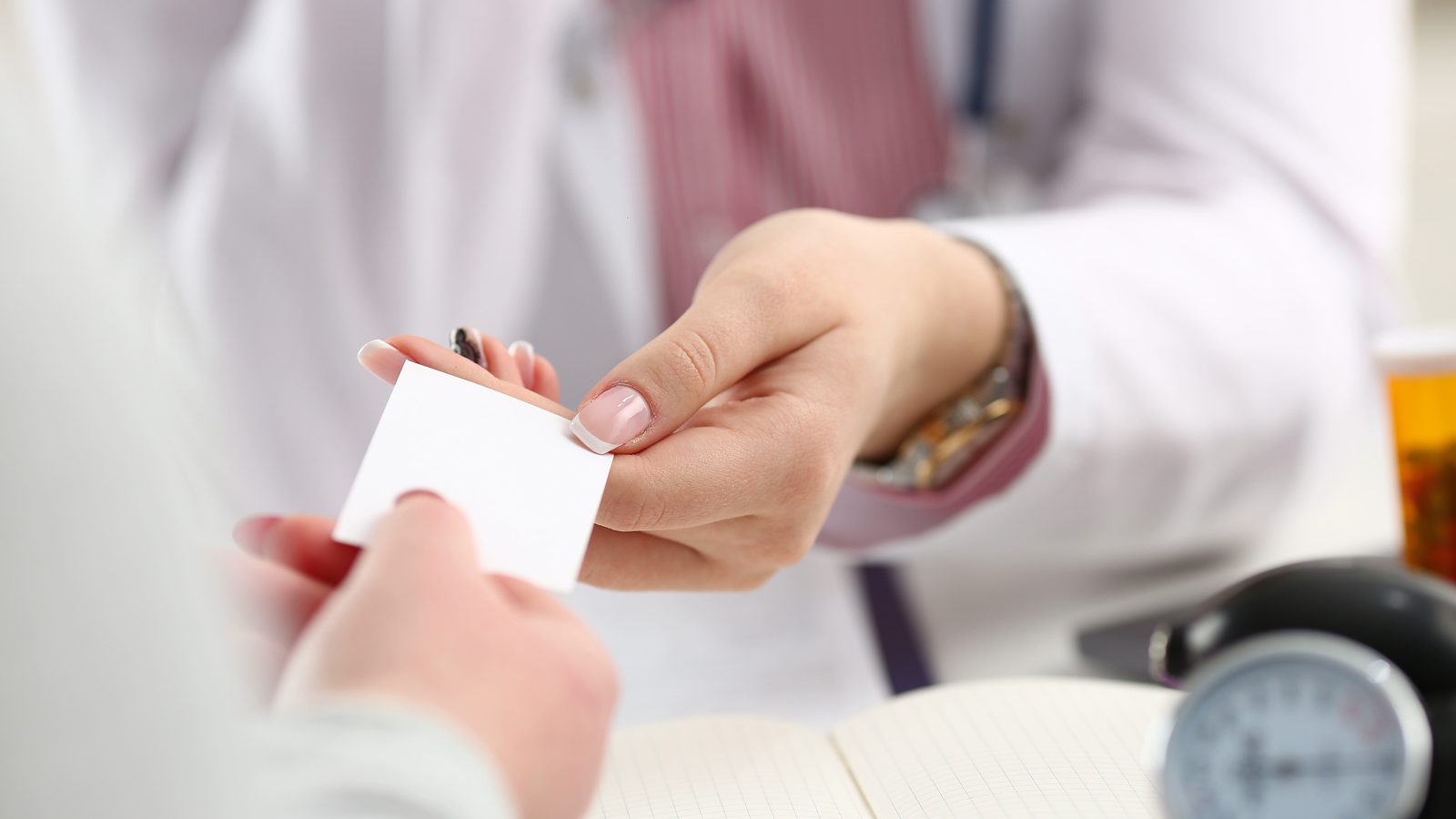 Female Doctor Hands Over White Card To Patient